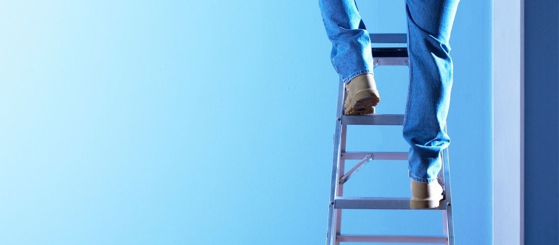 Building inspector on a ladder performing a building inspection