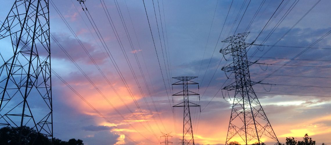 Three electrical transmission towers during a sunset