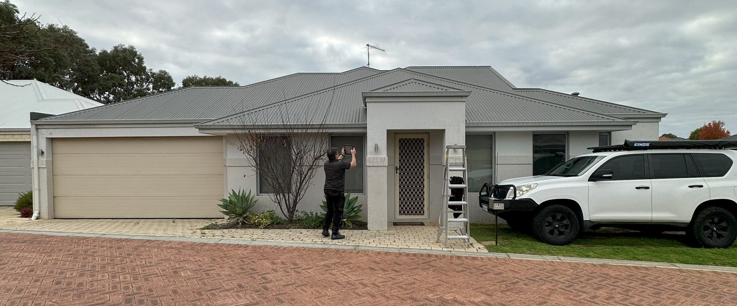 Male inspector out the front of single story home looking at render cracking